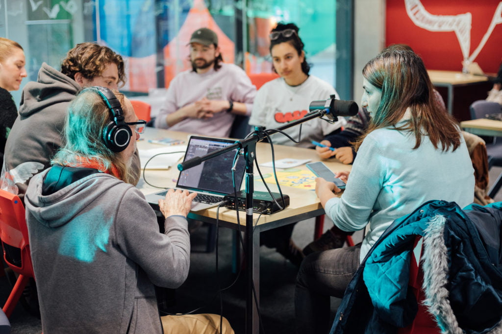 A group of people sitting around a table in the library with a microphone recording conversations