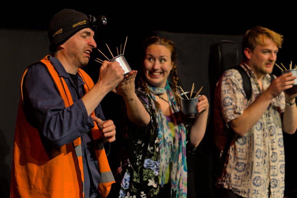 3 actors holding cups, dressed in costumes