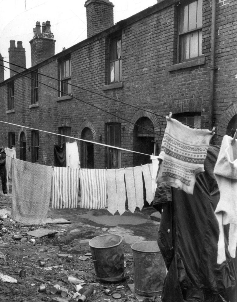 Image of sub-standard housing in Oldham. With line of terrace houses and washing pegged on washing lines.