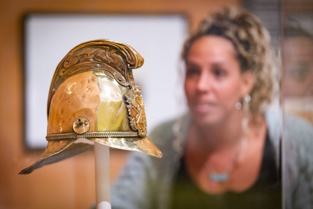 Visitor looking at Victorian firefighter helmet.