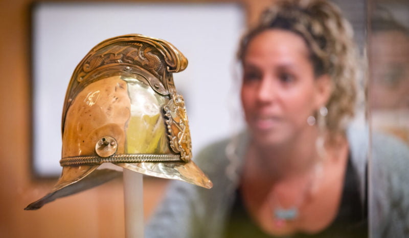 Visitor looking at Victorian firefighter helmet.