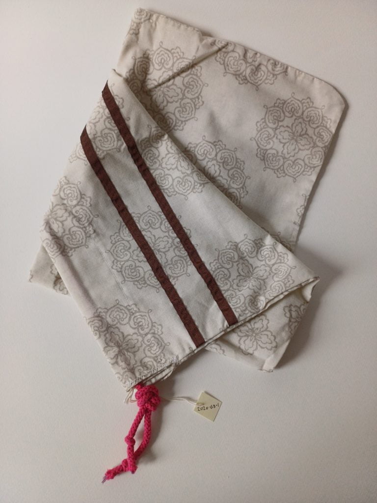 Image of a homemade fabric pattern scrub bag with red border and pink cord.