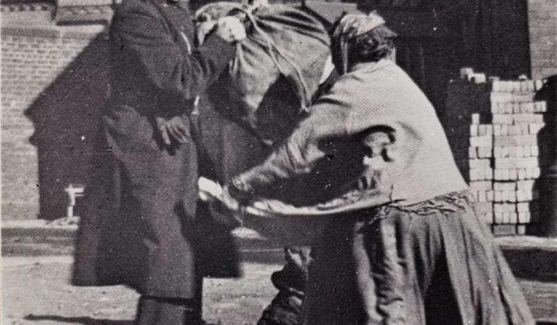 Black and white image of a police officer distributing coal to a women.