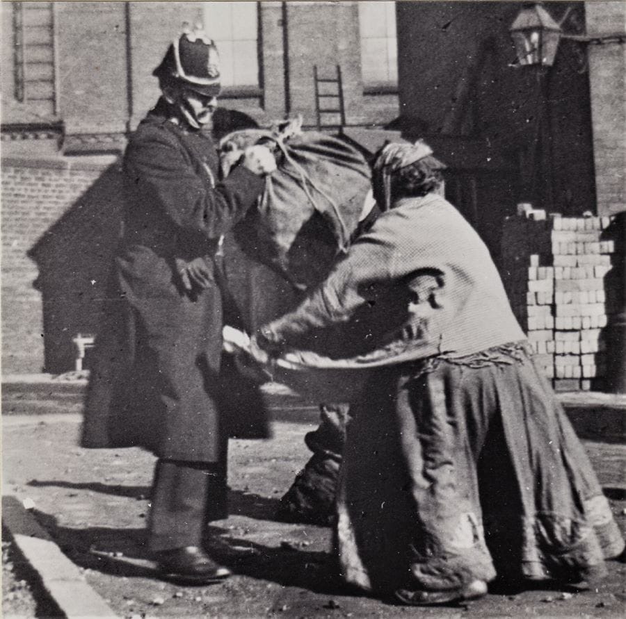 Black and white image of a police officer distributing coal to a women.