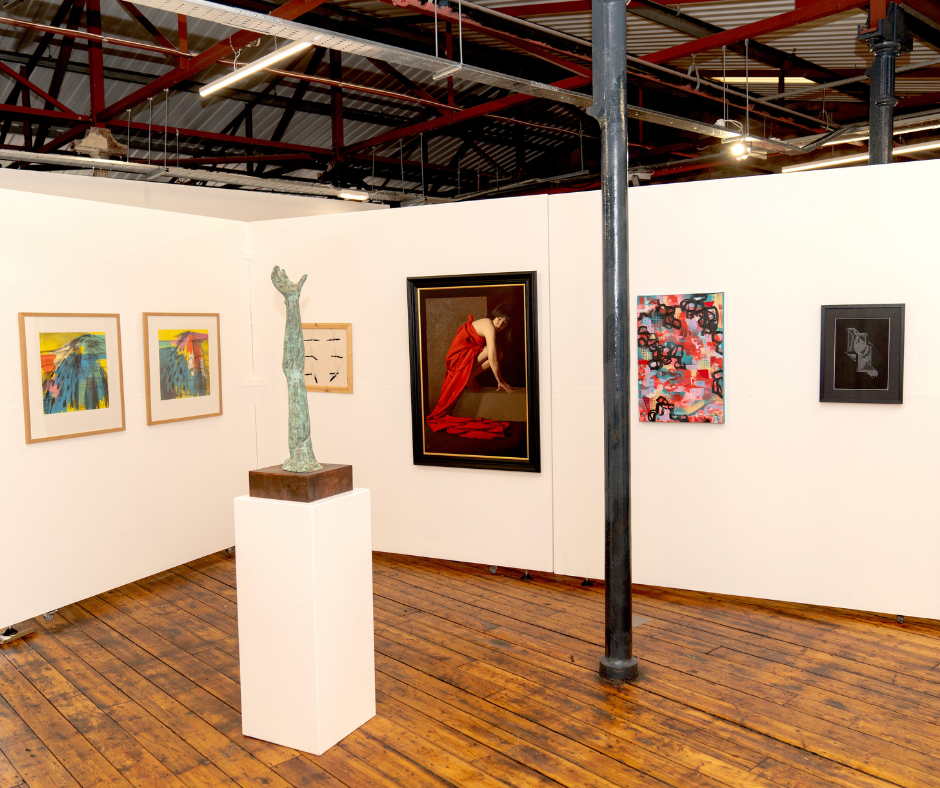 A view of the inside of 1853 Studios, with 6 artworks of various sizes on the wall and a sculpture on a plinth.