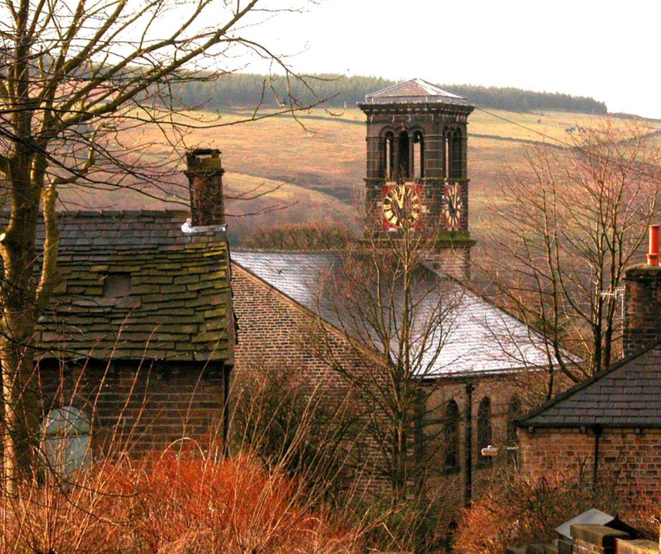 Autumnal photograph of Holy Trinity Dobcross with the clock tower in the background centre.
