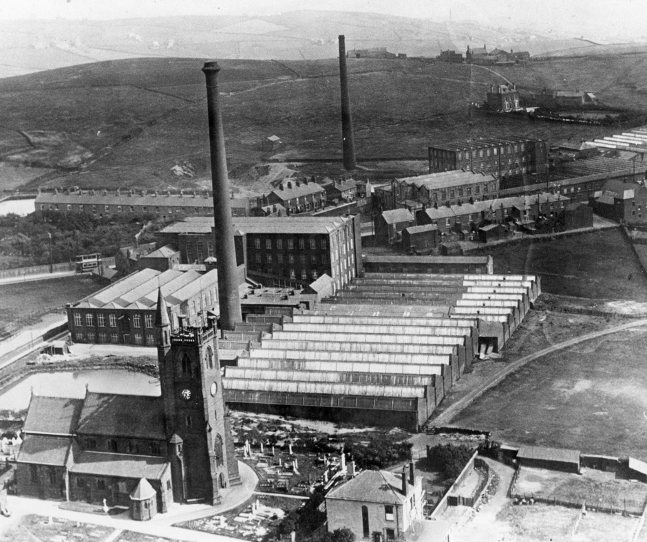 A black and white aerial view photograph of Moorside with the church and mills in focus.