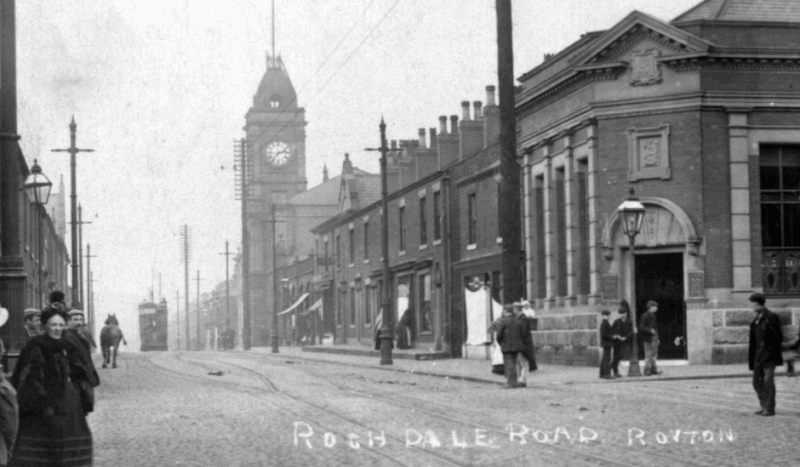 Black and white old photograph of Rochdale Road in Royton town centre, with the Town Hall and clock tower in the background centre.