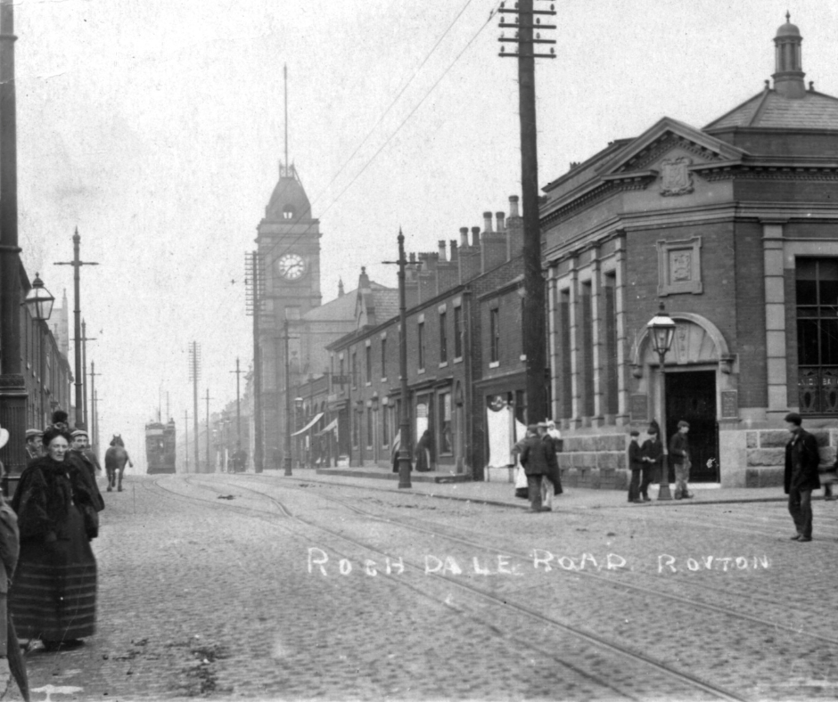 Black and white old photograph of Rochdale Road in Royton town centre, with the Town Hall and clock tower in the background centre.