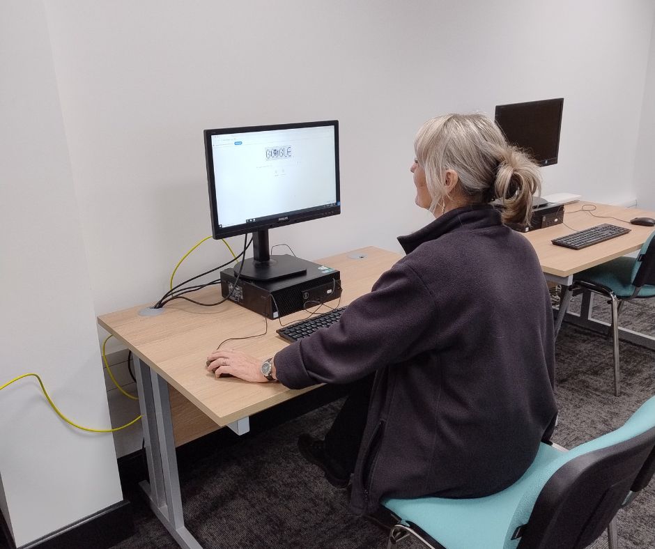 A member of the archives team using a computer in the new microfilm room at Oldham Archives.
