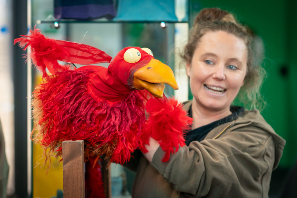 A lady holding a red bird puppet