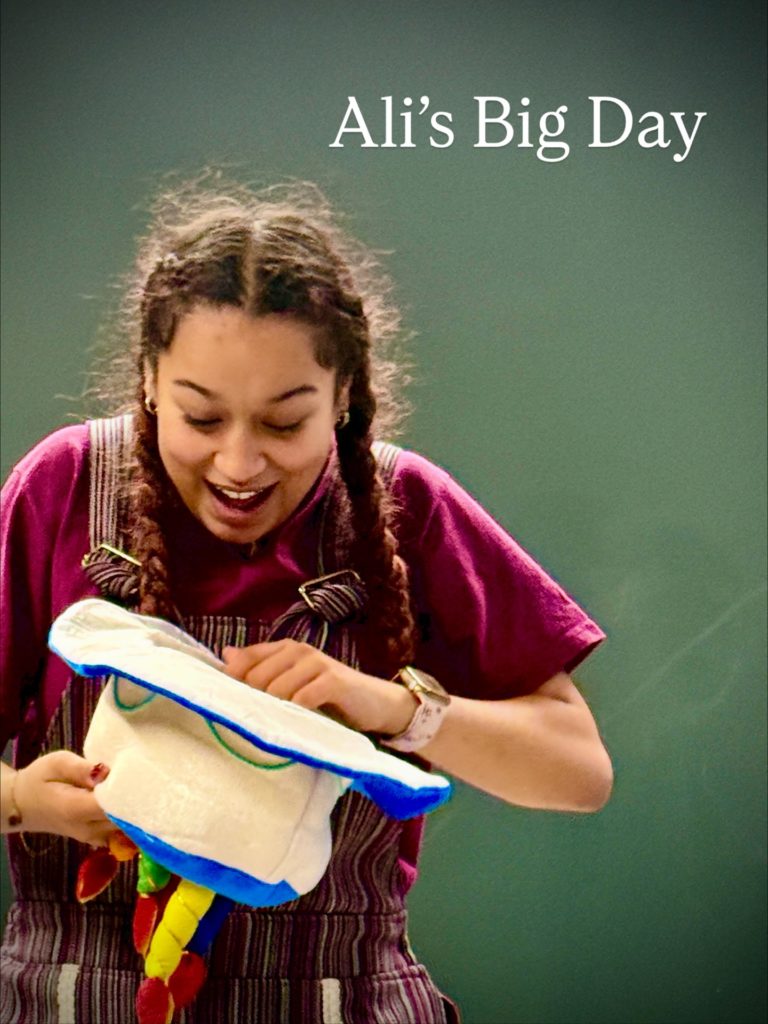 a Teenage girl wearing 2 plaits in her hair looking into an upside-down hat with birthday candles on it