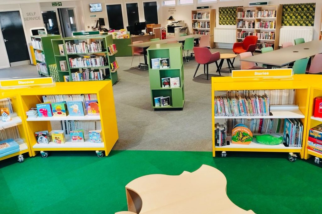 Some brightly coloured library shelves with chairs and tables